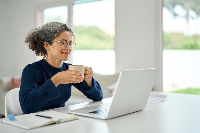 Smiling relaxed middle aged lady working on computer
