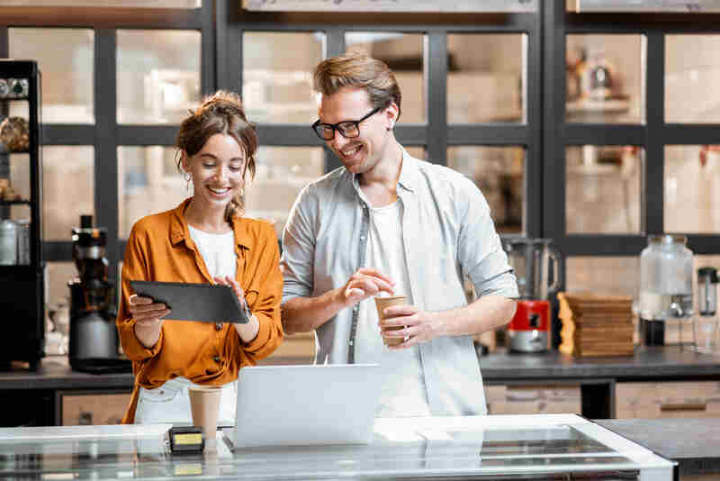 two small business shop owners standing with a digital tablet and a laptop