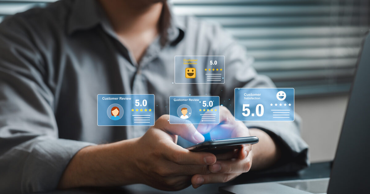 A man sitting at a desk holding an iPhone with an overlay of online reviews.